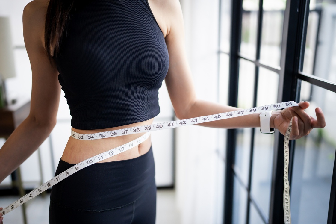 A woman holding a measuring tape around her waist